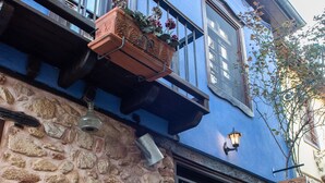 Un edificio con facciata in pietra, un balcone in legno e una porta decorata con un vaso fiorito.