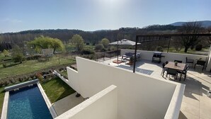 Una terraza en la azotea con piscina, mobiliario exterior y vistas al campo.