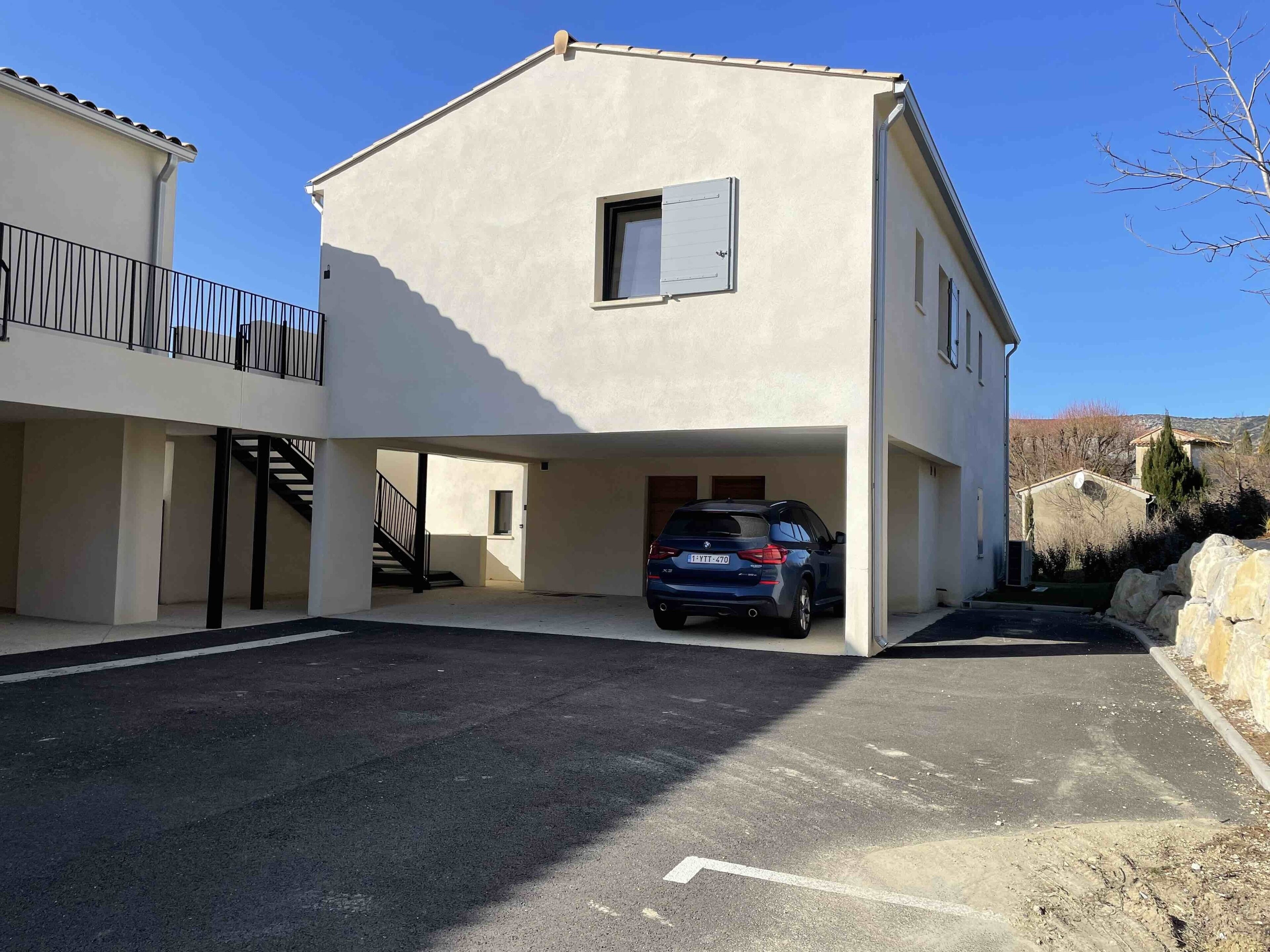 A two-story building with a car parked under the second floor.
