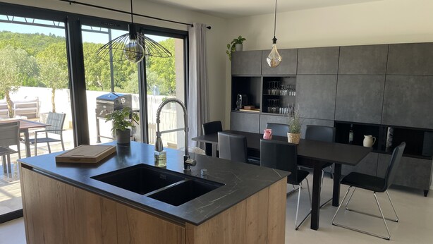 Una cocina moderna con una isla central, comedor y vistas al exterior.