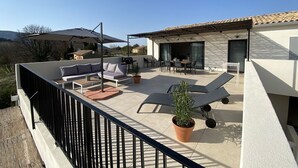 Una terraza en la azotea con mobiliario exterior, zona de barbacoa y plantas en macetas.