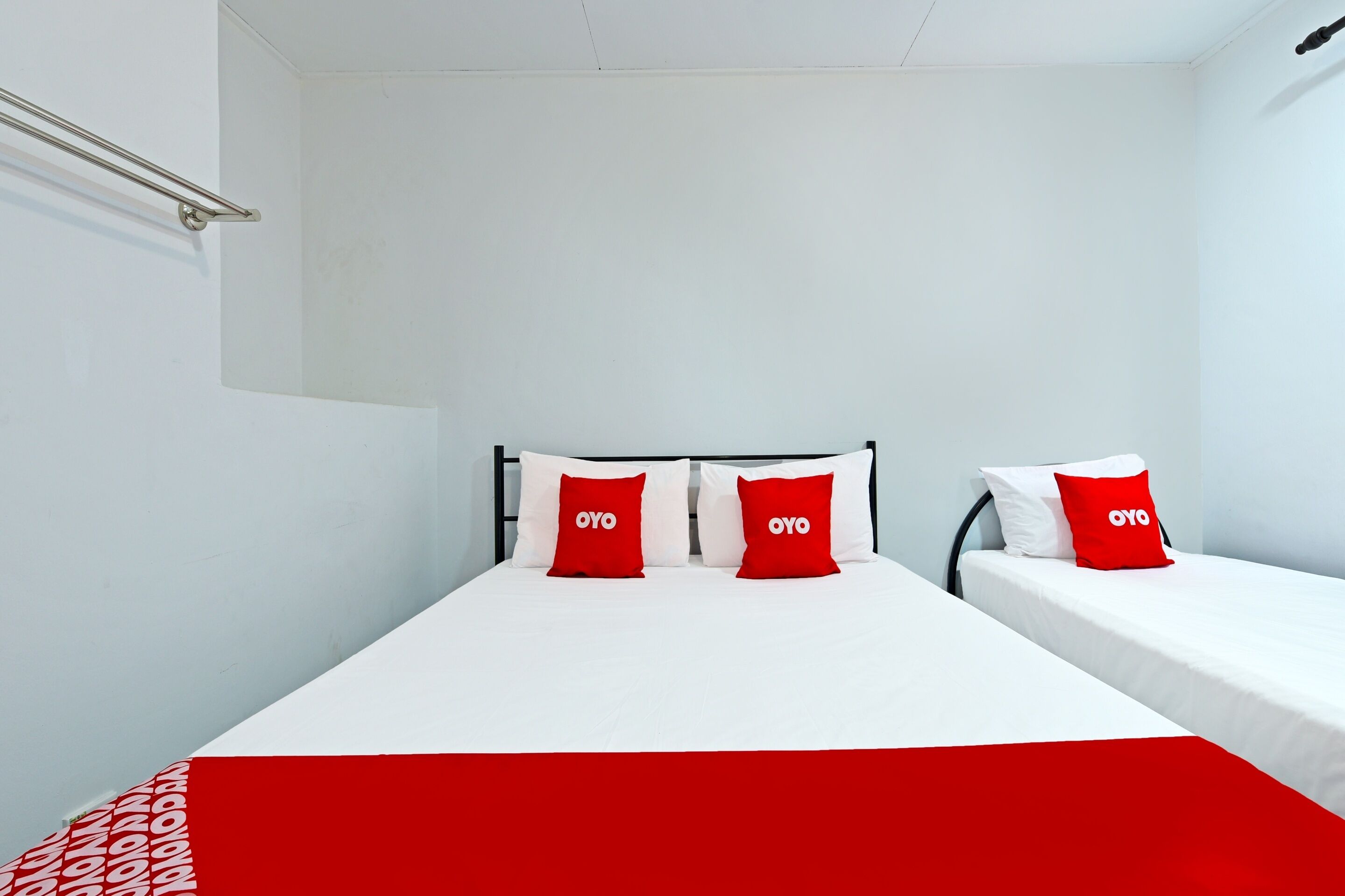 A bedroom with a bed, two pillows, a bedside table, and a red blanket.