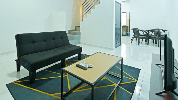 A modern living room with a black sofa, a wooden coffee table, and a TV on a stand. - OYO 90493 JL Homestay (Segamat)