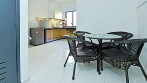 A kitchen with a refrigerator, stove, and sink. There is a dining area with a table and chairs. - OYO 90493 JL Homestay (Segamat)