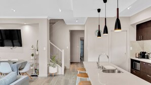 Cocina moderna con una isla grande, armarios blancos e iluminación colgante.
