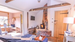 A cozy room with a fireplace, a bed, a table with a lamp, and a door. - The Forge (Stowmarket)