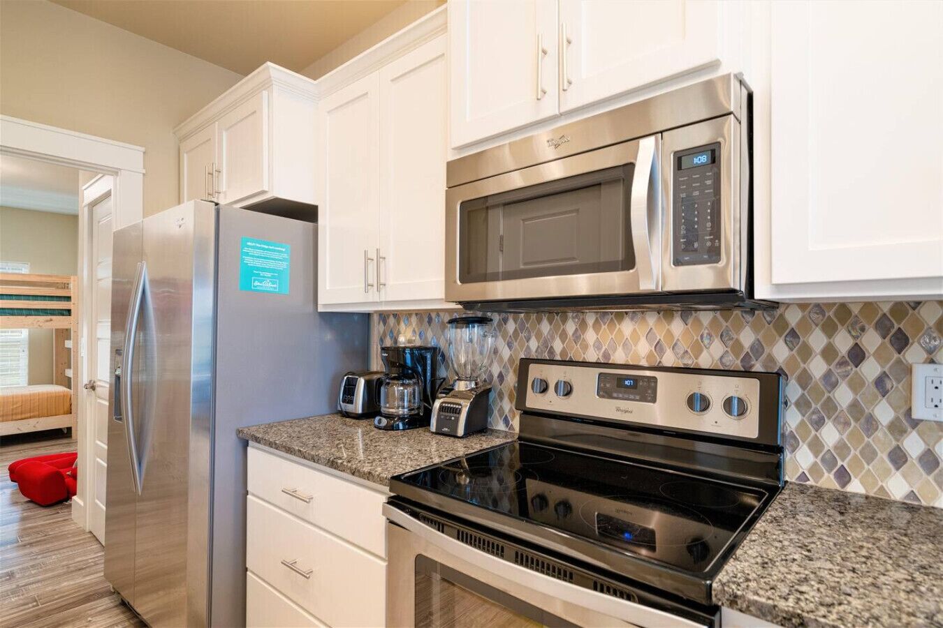 A compact kitchen with stainless steel appliances, including a refrigerator, microwave, toaster, and stove.