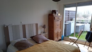 Ein Schlafzimmer mit einem Bett, einem Holzschrank, einem Nachttisch und Blick ins Freie.
