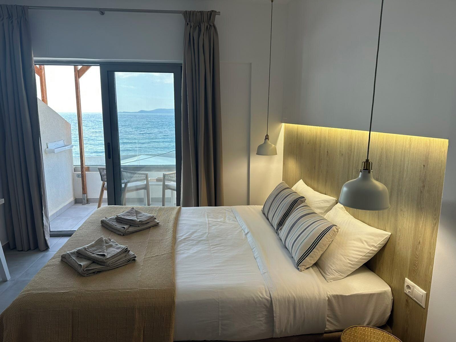 Ein Hotelzimmer mit Bett, Meerblick und einem Balkon mit Tisch und Stühlen.