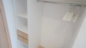 Una habitació amb un armari, una barra per penjar roba i un petit objecte negre a terra.