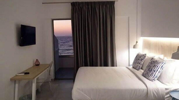 Habitació d'hotel amb llit, escriptori, televisió i vista a l'oceà per la finestra.
