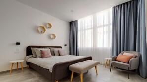 A modern bedroom with a large bed, a bench, a chair, and a small table. - Perfect Location, Modern 2BR Apartment (Sliema)