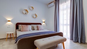 A modern bedroom with a bed, bedside tables, a bench, and decorative wall lights. - Perfect Location, Idyllic 2BR Apartment (Sliema)