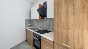 A modern kitchen with a black stove, white countertop, and patterned backsplash. - Perfect Location, Cosy 1BR Apartment (Sliema)