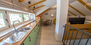 Une cuisine dotée d’un plan de travail en bois, d’un évier et d’un coin repas avec une table et des chaises.