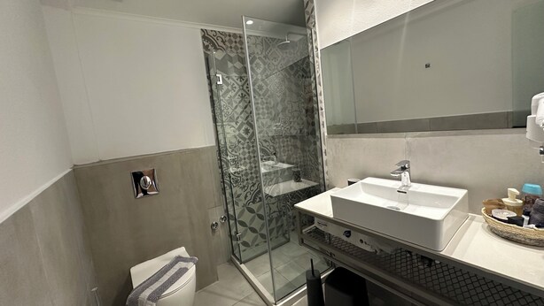 A modern bathroom with a glass shower enclosure, a white sink, and a toilet. - Anfi Suites 5 - Sea View & Sunset Balcony - 4 guests (Kato Gouves)