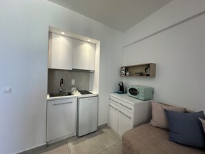 A compact kitchenette with a built-in oven, microwave, and sink.