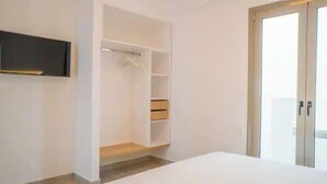 Quarto com cama, guarda-roupa e televisão na parede.