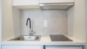 Uma cozinha moderna com uma pia de aço inoxidável, uma torneira preta e um fogão por indução embutido.