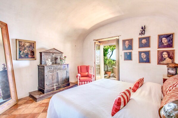 Un dormitorio con una cama, un aparador, una silla y una puerta que da al exterior.