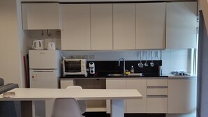 A modern kitchen with white cabinets, a built-in microwave, a gas stove, and a dining area with a table and chairs. - Modern, cosy and practical place (Montevideo)