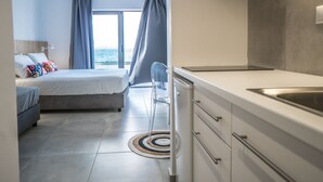 Quarto de hotel moderno com cama, escrivaninha e vista para o mar.
