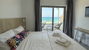 Quarto de hotel com cama, escrivaninha e vista para o mar.