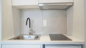 Uma cozinha com uma pia de aço inoxidável, uma torneira preta e um fogão por indução embutido.