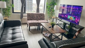 A modern living room with a sofa, armchair, and a flat-screen TV. - 2BR apt close to EWR Airport m5og (Elizabeth)