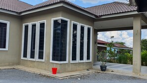 A house with a covered porch, large windows, and a potted plant. - OYO Home 90496 Delima Homestay (Alor Setar)