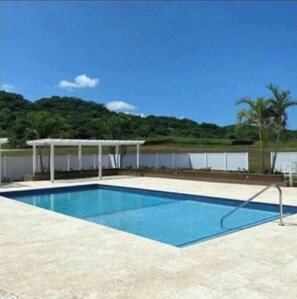 A rectangular swimming pool with a white deck and a metal ladder.