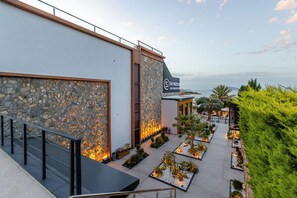A modern building with a stone facade, a sign reading 'SA REZVA,' and a landscaped outdoor area with plants and a seating area. - Cesme Sarezya Boutique Hotel  (Cesme)