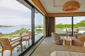 A modern room with a large glass window, a sofa, a table, and a hanging light fixture. - Cesme Sarezya Boutique Hotel  (Cesme)
