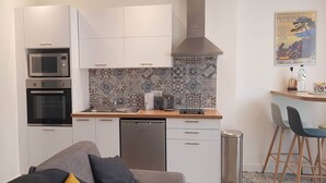 A compact kitchen with white cabinets, a microwave, oven, and a coffee maker.