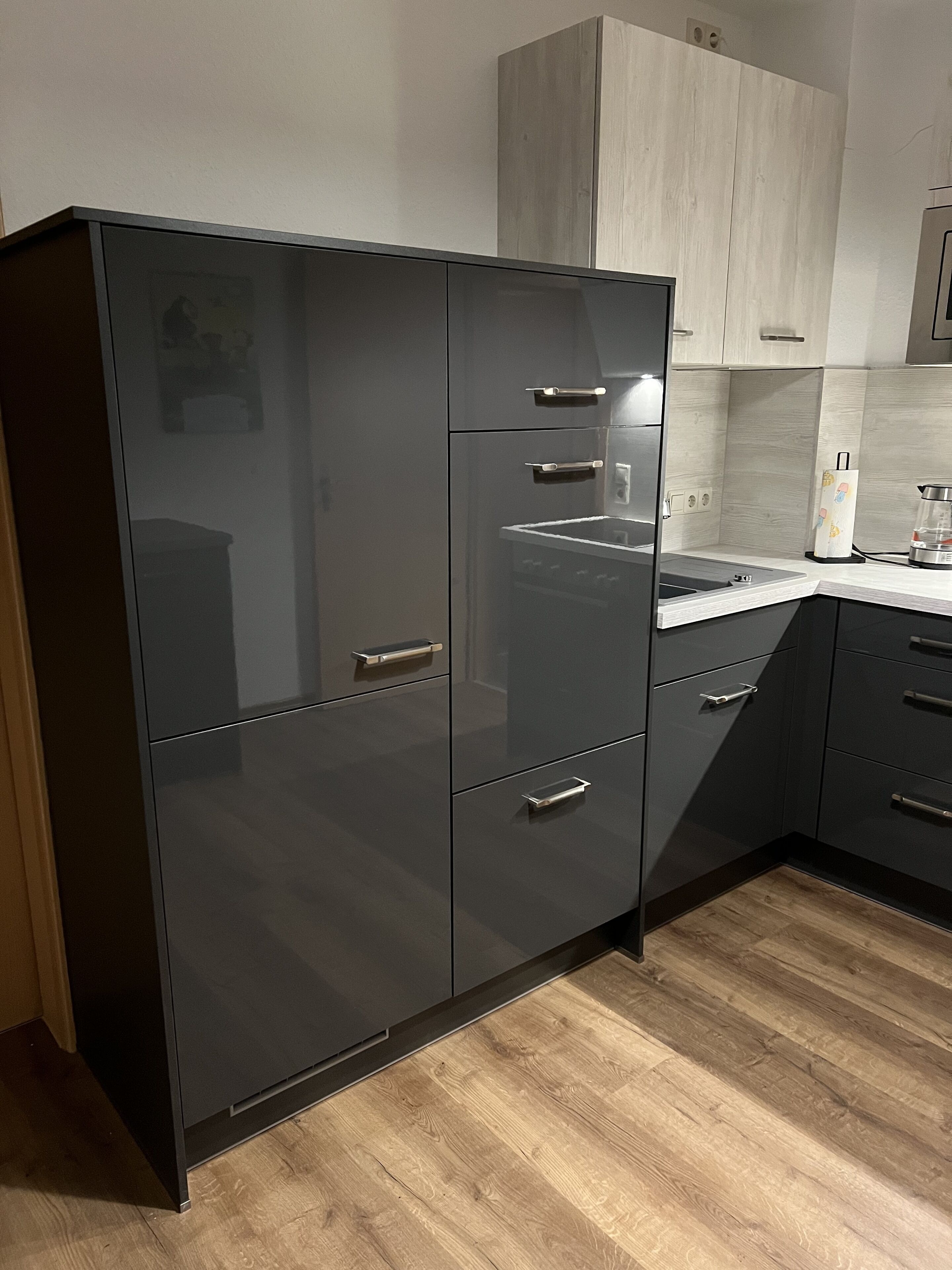 A modern kitchen with dark cabinetry, a wooden countertop, and a built-in oven.