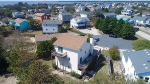 Un quartier résidentiel avec des maisons, un grand immeuble blanc doté d’un balcon et une vue sur la mer.