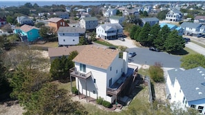 Un quartier résidentiel avec des maisons, un grand immeuble blanc doté d’un balcon et une vue sur la mer.
