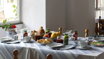Mesa de café da manhã posta com diversos alimentos, utensílios e acompanhamentos.