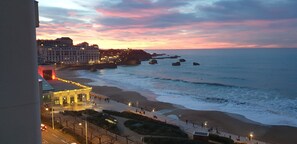 A coastal view with a promenade, buildings, and rocky outcrops.