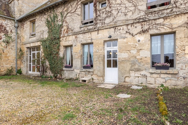 Un bâtiment en pierre avec un jardin à l’avant.