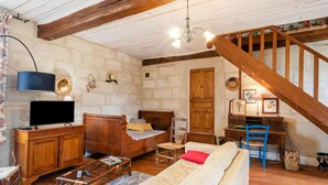 Un salon confortable avec un escalier en bois, un lit, un bureau et un téléviseur.