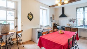 Une cuisine avec une table rouge, des chaises en bois, un four blanc et une hotte noire.