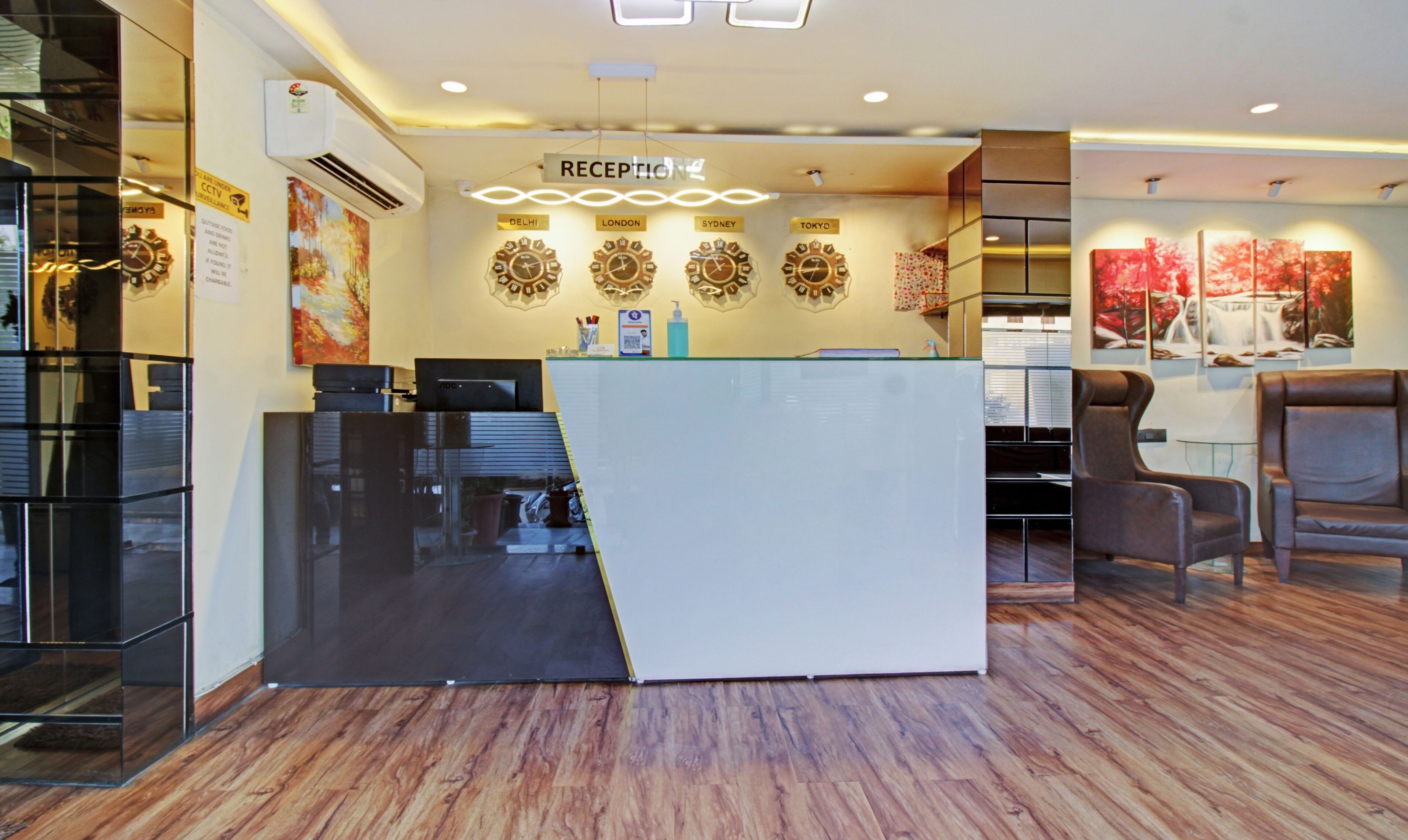 A reception area with a modern design, featuring a reception desk, a clock, and a sign indicating the direction to the reception.