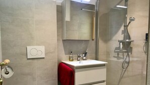 A modern bathroom with a toilet, sink, and shower.