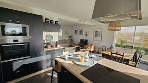 Una cocina moderna con horno empotrado, un comedor con mesa y sillas de madera, y un amplio ventanal con vistas al exterior.