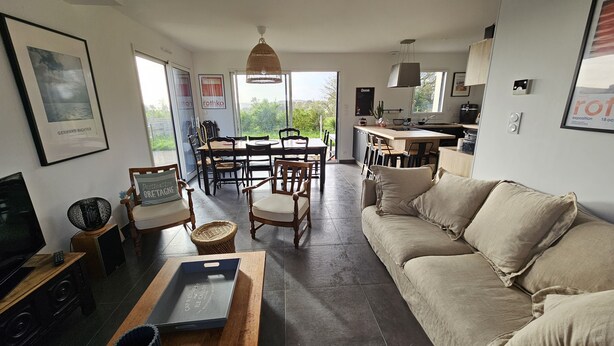 Un amplio espacio de sala con sofá, mesa de comedor, sillas y cocina al fondo.