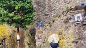 A stone wall with a blue plaque, a metal sculpture, and a potted plant. - New flats In the historic old town in the pedestrian zone (Dillenburg)