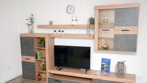 A modern entertainment unit with a flat-screen TV, built-in shelving, and decorative items. - New flats In the historic old town in the pedestrian zone (Dillenburg)