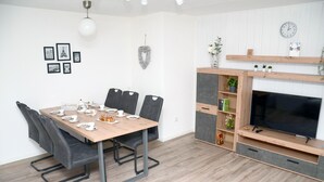 A modern living room with a dining table set for tea, a TV, and a cozy seating area. - New flats In the historic old town in the pedestrian zone (Dillenburg)