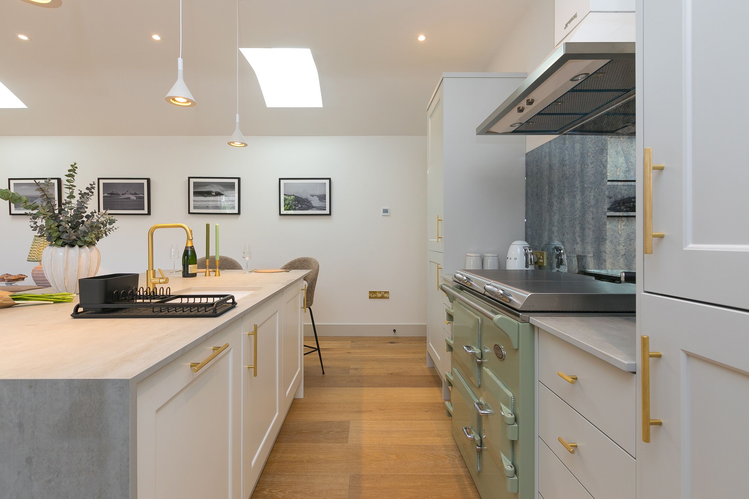A modern kitchen with a central island, stainless steel appliances, and a wooden floor.